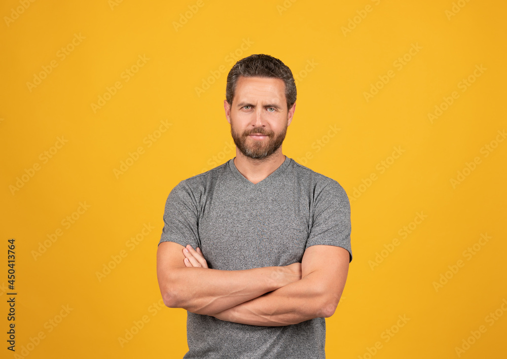 handsome mature muscular man with beard smiling on yellow background crossed hands, male beauty handsome mature muscular man with beard smiling on yellow background crossed hands, male beauty
