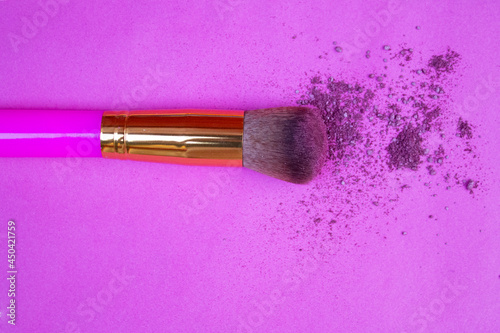 MAQUILLAJE EN POLVO CON BROCHA DORADA SOBRE FONDO ROSA