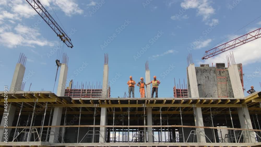 Tower cranes and workers at high concrete residential building under construction. Real estate development concept. Tower cranes and workers at high concrete residential building under construction. Real estate development concept.