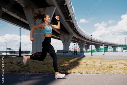 A confident female running coach does strength exercises in the open air. Healthy lifestyle concept. Slim figure and comfortable clothes. © muse studio