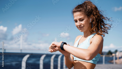 Smart modern cardio watch measuring calorie burning. Break a confident brunette woman leads a healthy lifestyle. The athlete prepares for running, does a warm-up stretching of her body.