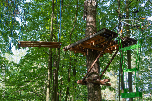 Bike on a rope with a shifted center of gravity for balance. Obstacle course in rope park at height in the foliage of the trees. Outdoor activities. Adventure among  foliage of trees in the forest. 