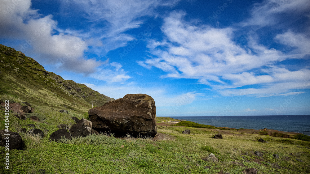 Hawaii beach with hills, blue sky, white clouds, rock formation