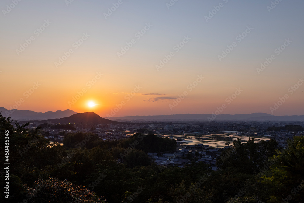 奈良の盆地に沈む夕陽と輝く水田
