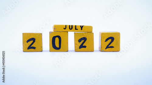 Wooden block calendar for July 2022. Yellow on a white background