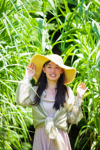 高い草の茂みにいる若い笑顔の女性のポートレイト