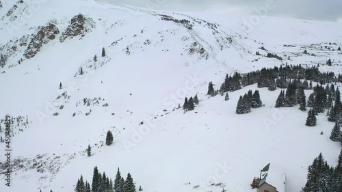 Thick Snow-Covered Mountain Slopes With Isolated Cottage In Winter Park Of Colorado. - Aerial Drone Shot photo