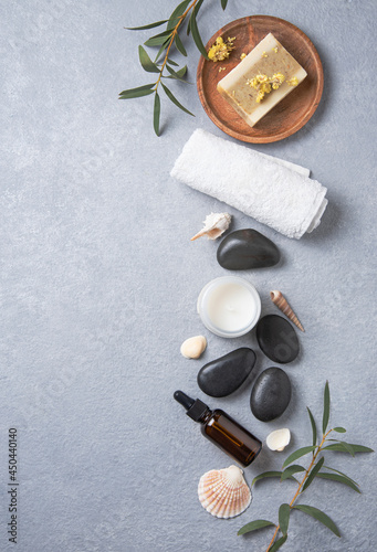 Concept flat lay beauty spa with natural cosmetic products peeling natural soap, massage stones and oil on blue background. Top view and copy space