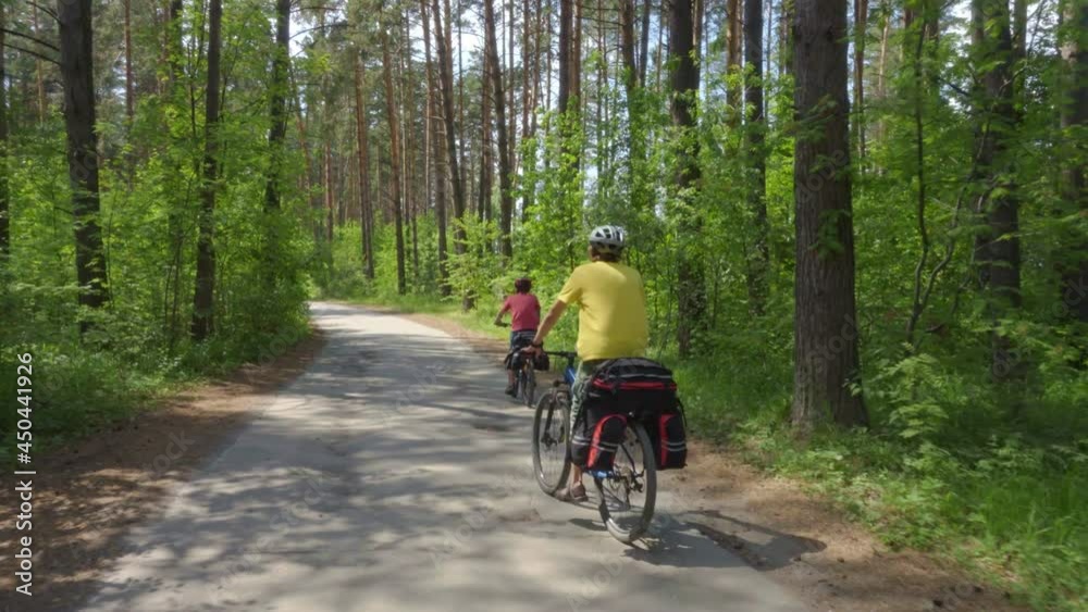 Two teenagers travel on bicycles. Young men on bicycles with cycling backpacks ride along a picturesque forest road. Two teenagers travel on bicycles. Young men on bicycles with cycling backpacks ride along a picturesque forest road.