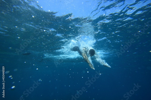 underwater photo of man diving into the refreshing clear blue ocean