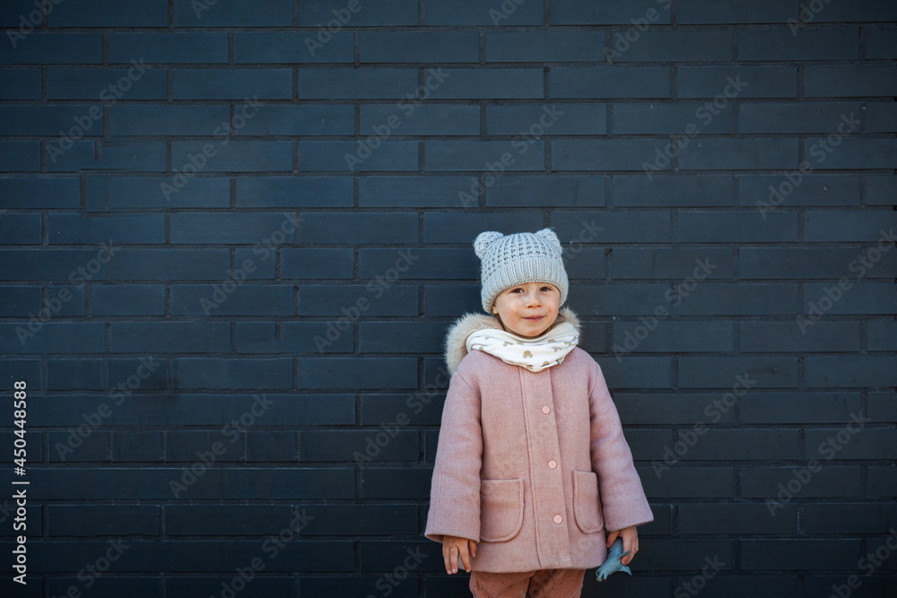 Happy cute little girl smiling against the dark brick wall Happy cute little girl smiling against the dark brick wall