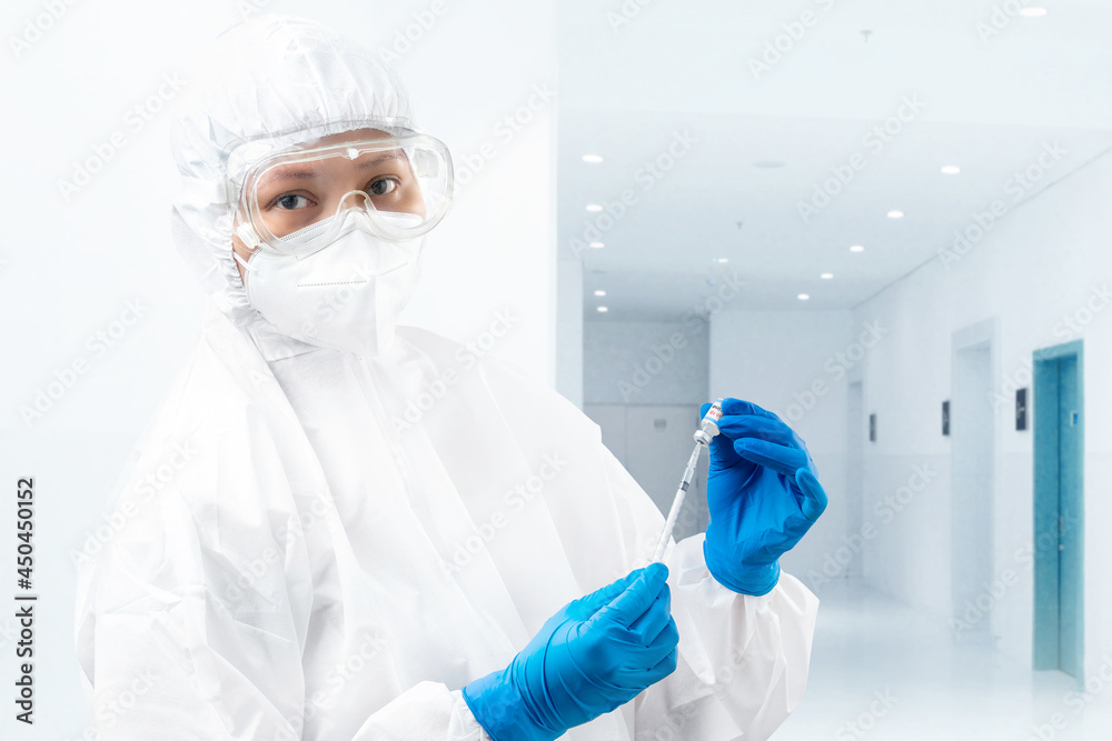Health worker woman with a protective suit and gloves holding covid 19 vaccines Health worker woman with a protective suit and gloves holding covid 19 vaccines