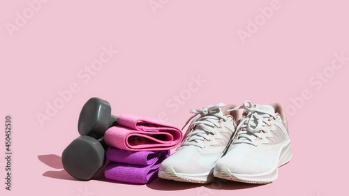 Female sneakers, booty bands and on pink background for intensive full body workout.