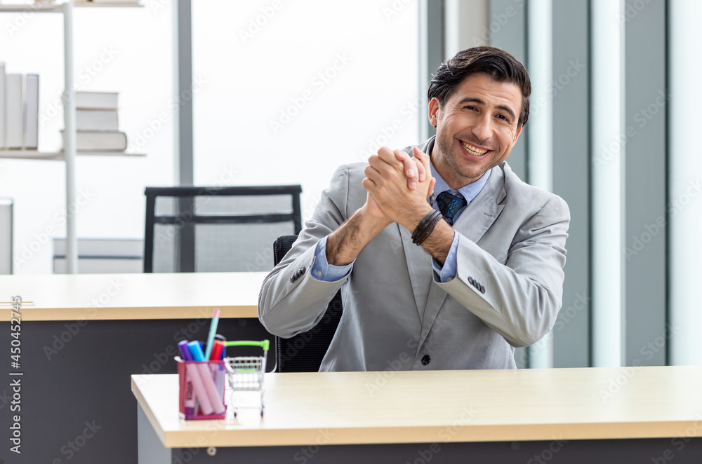 Portrait of a businessman wearing a suit Sitting at my desk smiling and pretending to be successful and glad working in the office. Portrait of a businessman wearing a suit Sitting at my desk smiling and pretending to be successful and glad working in the office.