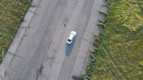 Aerial shot of white car riding through empty road.  photo