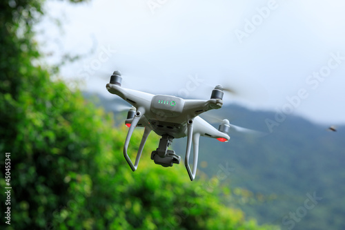 White drone with camera flying in summer mountains