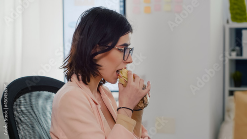 Foto Entrepreneur woman eating tasty sandwich having work break working in business company office during takeout lunchbreak