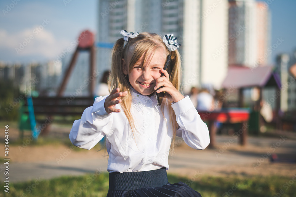 Little girl on the street talking on the phone and writing a message Little girl on the street talking on the phone and writing a message
