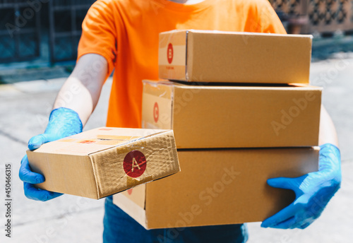 Delivery service courier sending boxes mail to customer while wearing glove for protect herself in covid-19 pandemic outbreak. Conceptual of hygiene service in covid-19 pandemic.