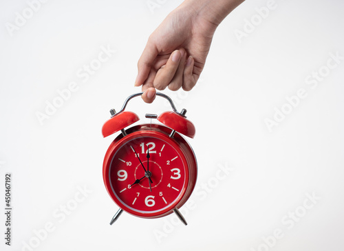 Female hand holding alarm clock on white background, copy space, conceptual