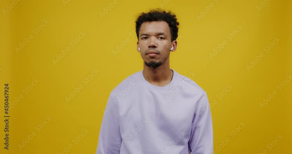 A young man wears in wireless headphones answers call and starts talking A young man wears in wireless headphones answers call and starts talking