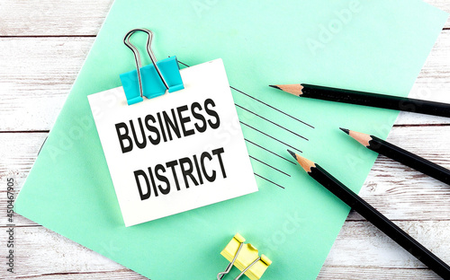 Text BUSINESS DISTRICK on the short note with pencils on the wooden background photo