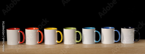 7 white mugs of rainbow colors on a dark background photo