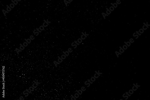 Falling snow on a black background. small particles with bright dots starry sky.   haotic white bokeh. light spots texture. abstract.