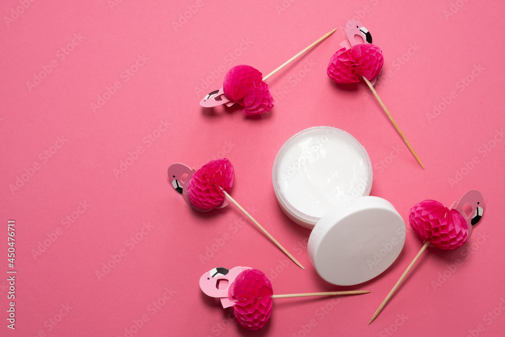 pink party toothpicks in a shape of flamingo and face cream on a pink background. origami pink party toothpicks in a shape of flamingo and face cream on a pink background. origami