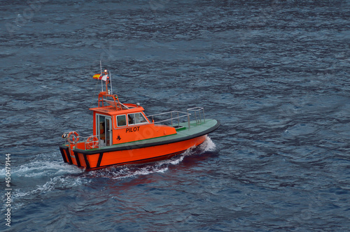 Spanish orange pilot boat sailing in the sea.