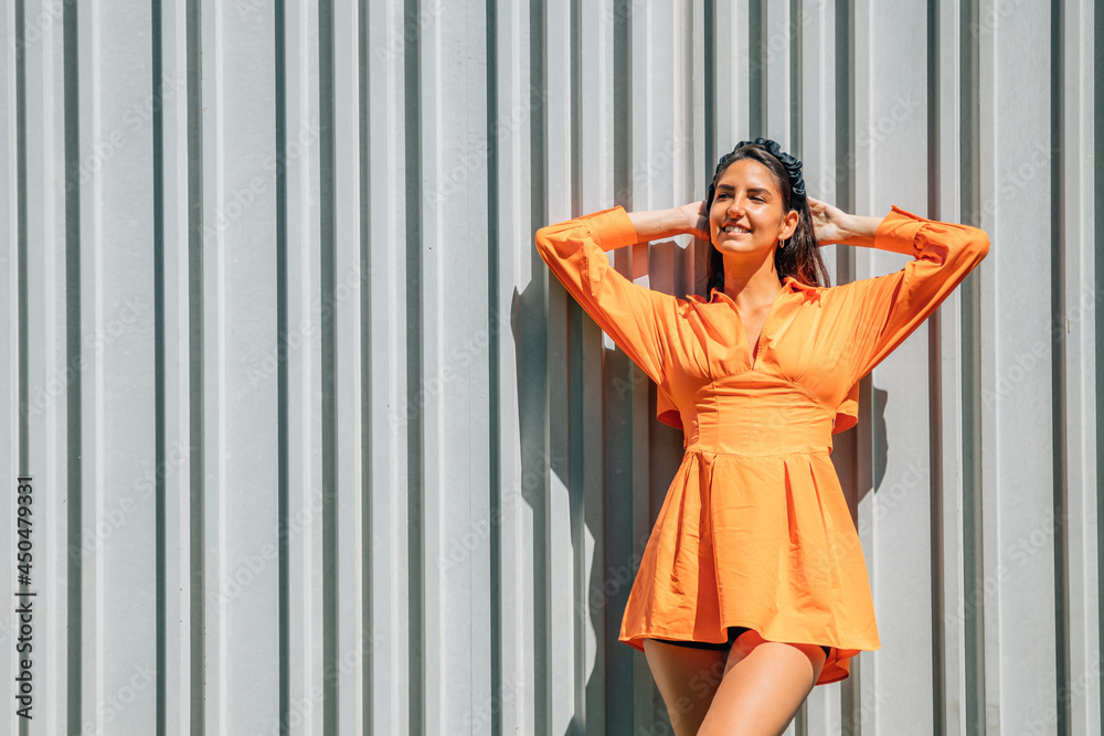 Fototapeta premium young girl in orange dress on the street wall outdoors
