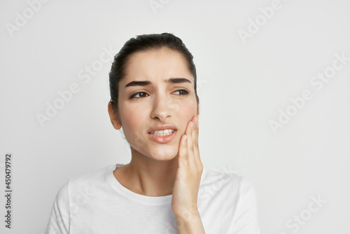 Woman in white t-shirt holding face toothache dentistry treatment