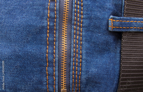 A fragment of blue jeans with a back zip pocket and a black nylon belt