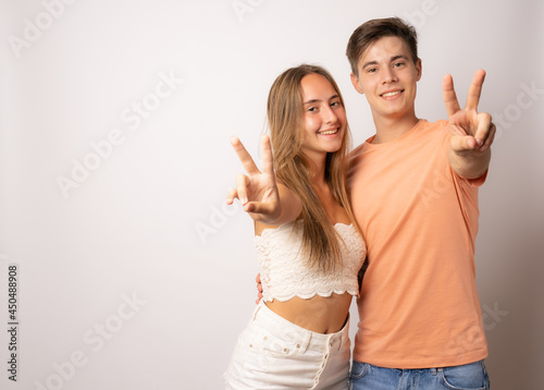smiling young casual couple making victory or peace sign on white background