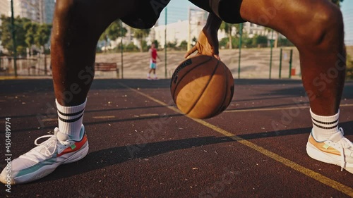 Close-up of a young black basketball player dribbling the ball across the field. Male athlete training on the basketball court