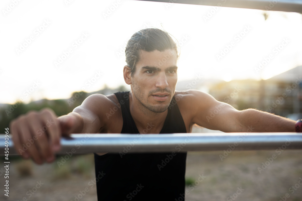 Naklejka premium Sporty athletic man exercises at the beach. Handsome man training outdoors