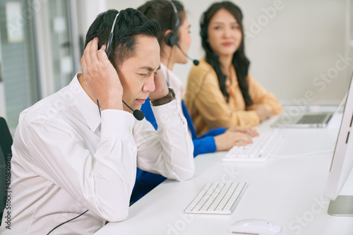 Asian male call center stressed in his job from support customer issue with team in office