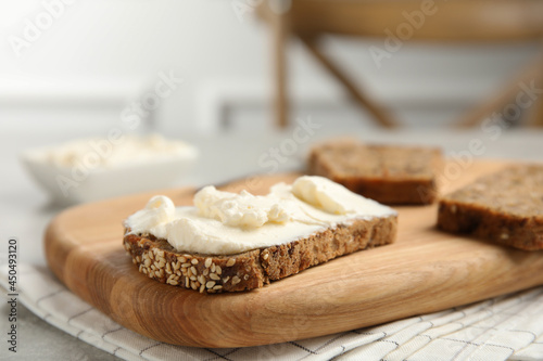 Bread with cream cheese on wooden table, closeup