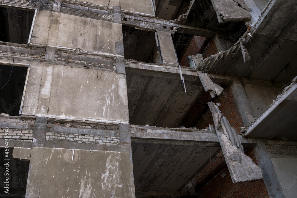 A ruined house without external walls with concrete blocks hanging on steel reinforcement. The concept of demolishing old buildings. Background A ruined house without external walls with concrete blocks hanging on steel reinforcement. The concept of demolishing old buildings. Background
