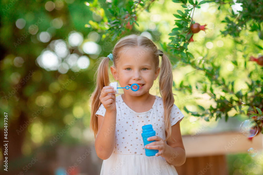 a little girl blows soap bubbles in the park a little girl blows soap bubbles in the park