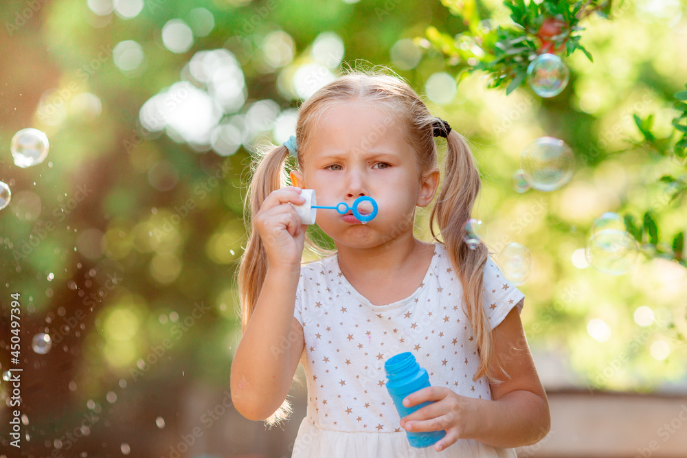 funny funny little blonde girl blowing soap bubbles in summer in the park funny funny little blonde girl blowing soap bubbles in summer in the park