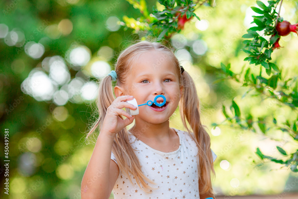 a little girl blows soap bubbles in the park a little girl blows soap bubbles in the park
