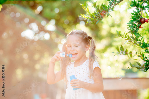 a little girl blows soap bubbles in the park