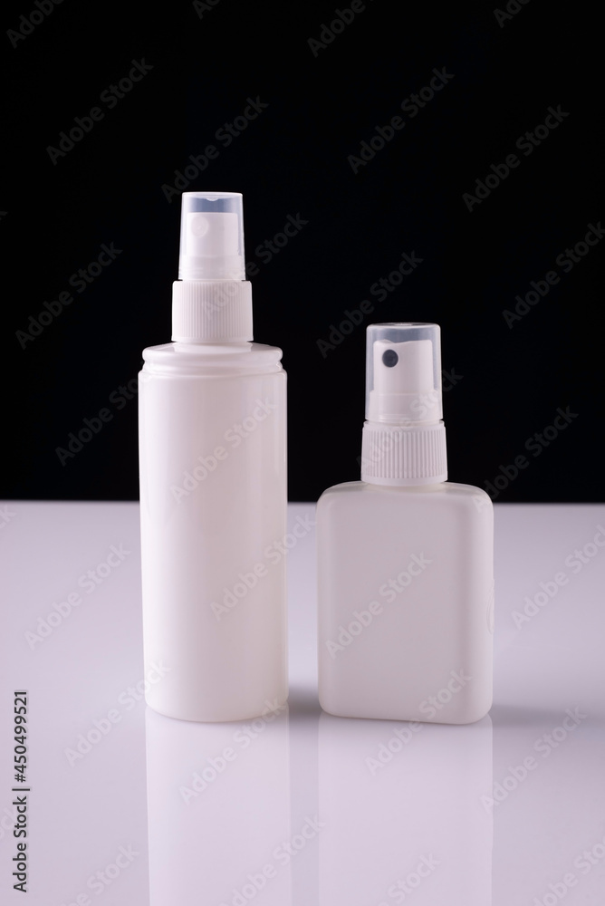 white aerosol bottles on white table and black background white aerosol bottles on white table and black background