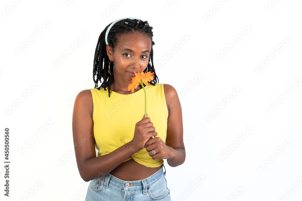 Woman smelling an orange flower looking at camera. White background. African-Ethiopian black woman. Woman smelling an orange flower looking at camera. White background. African-Ethiopian black woman.