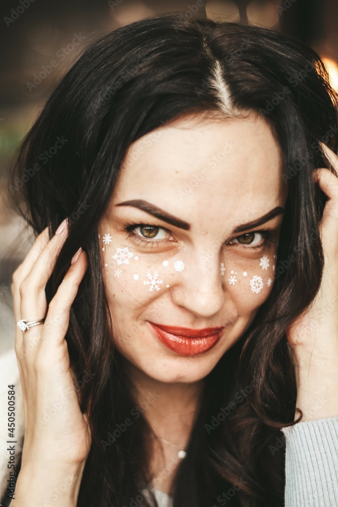 girl with New Year's makeup. snowflakes on the cheeks of a girl girl with New Year's makeup. snowflakes on the cheeks of a girl