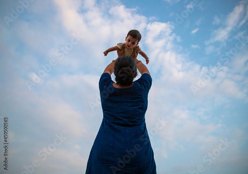 portrait of a indian mother playing with new born baby.