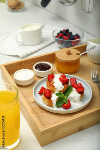 Delicious cottage cheese pancakes with fresh strawberries sour cream and mint served on white countertop