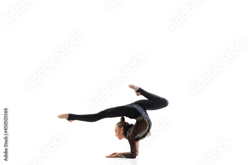 Young beautiful little girl, rhythmic gymnastics artist in sports stage costume isolated on white studio background. Concept of sport, action, active lifestyle