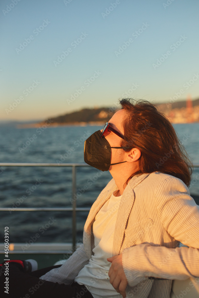 Woman with mask and sunglasses on a commuter boat.